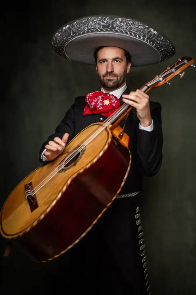 Man in mariachi-outfit met gitaar en sombrero, optredend tijdens Mariachi Los Tarascos avond, traditionele Mexicaanse muziek en cultuur.