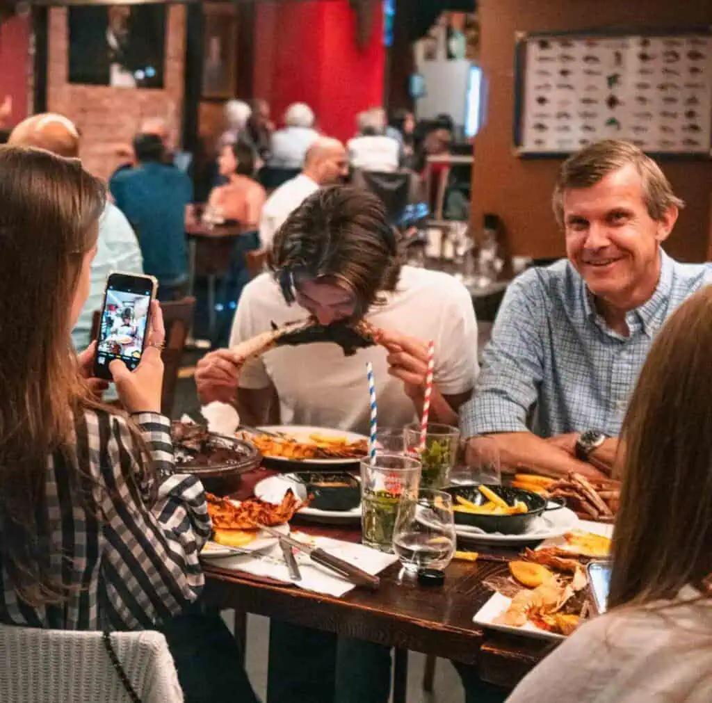 Gezellige sfeer bij Las Mañas met vrienden die genieten van een feestmaal, inclusief een vrouw die de tradionele Moors hoofdteloot eet, iedereen heeft plezier in een authentiek Spaanse ambiance.