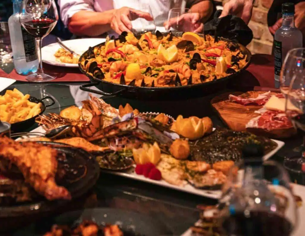 Grand bol de paella aux fruits de mer et aux crevettes entouré de convives dégustant un repas espagnol à Las Mañas.