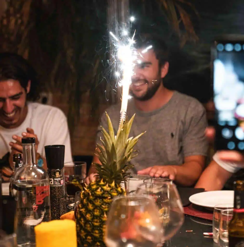 Gevierde feestavond bij Las Mañas met een ananas en vuurwerk, gezellige sfeer, vrienden lachen en genieten van een verjaardag of speciale gelegenheid in een restaurant.