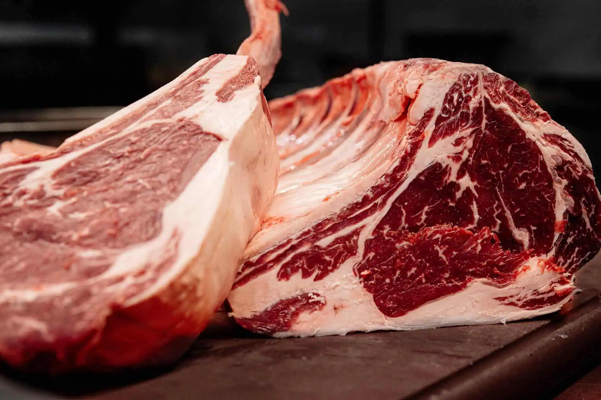 Des morceaux de bœuf marinés très juteux sur une planche à découper en bois, prêts à être préparés.