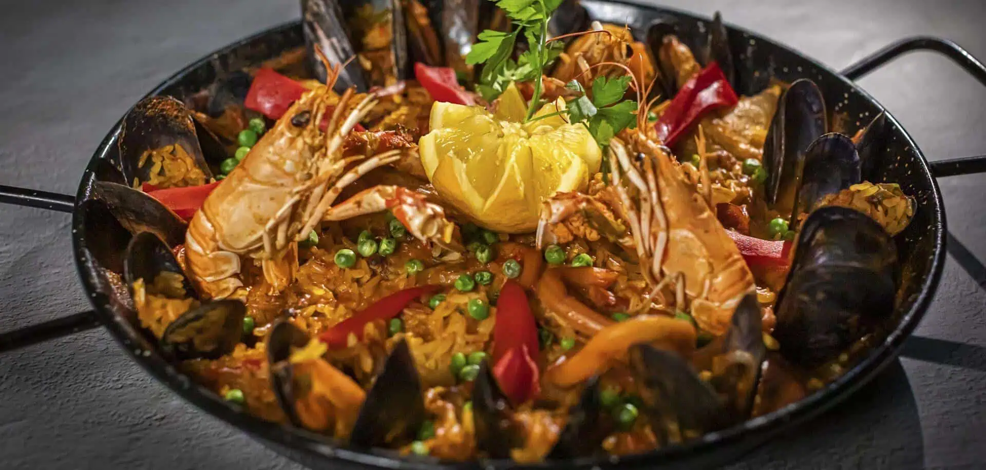 SMA Visschotel met groenten en gekookte citroen, geserveerd in een traditionele paella pan, perfect voor een authentieke Spaanse eetervaring.