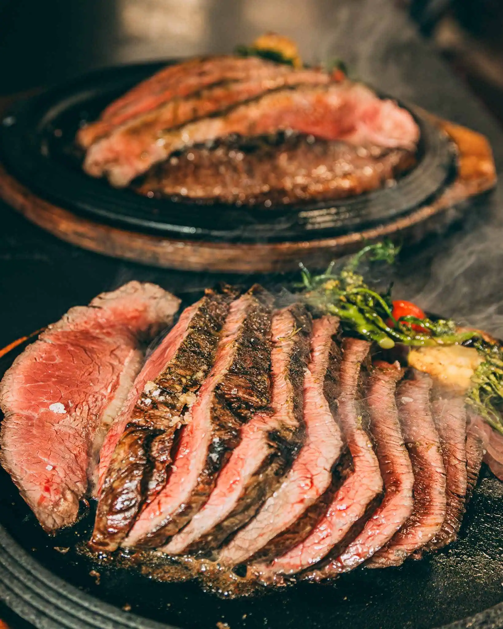 Steak grillé juteux sur une assiette en fonte chaude avec des légumes frais, prêt à être servi à Las Mañas, votre restaurant de tapas préféré en Belgique.