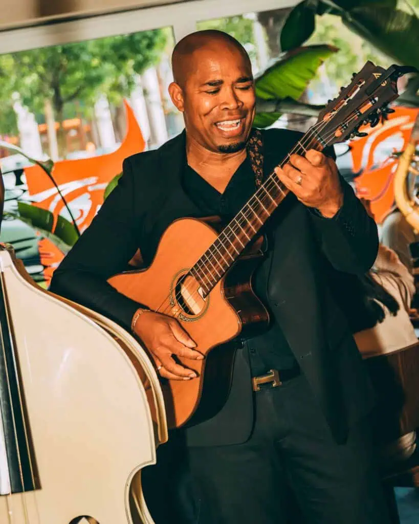 Image défendue d'un musicien jouant intensément de la guitare lors d'un concert à Las Mañas, avec un arrière-plan naturel et une ambiance atmosphérique.