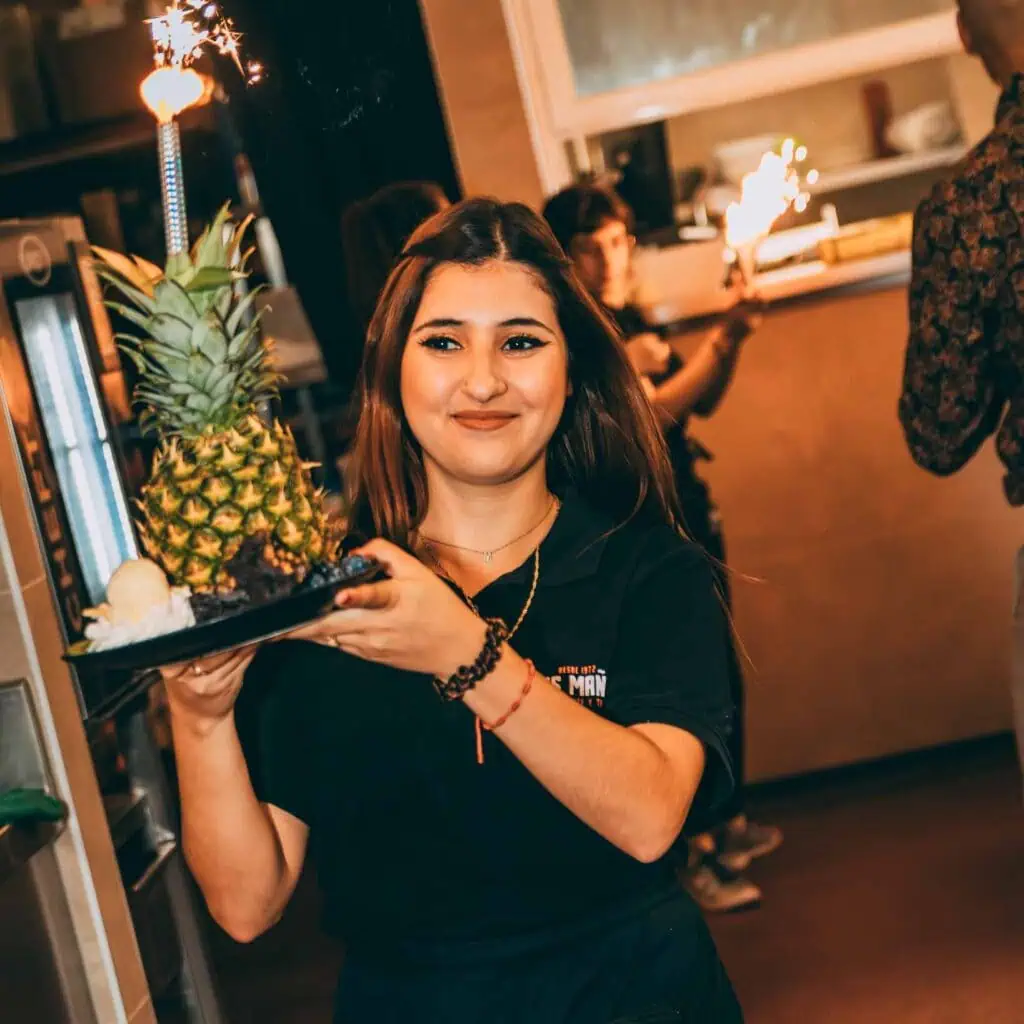 Belle serveuse avec des ananas tropicaux et des baies à Las Mañas, atmosphère joyeuse dans un restaurant, hospitalité et présentation culinaire, restauration et occasion festive, intérieur tropical et moderne.