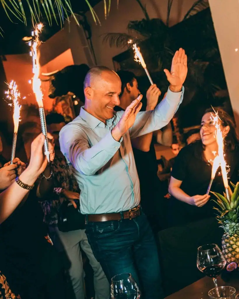 Des personnes en fête avec des cierges magiques et dansant lors d'une soirée amusante à Las Mañas, un restaurant à Bruxelles.