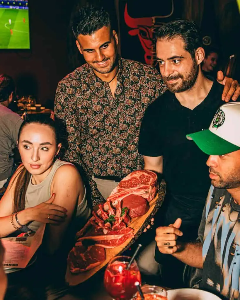 Geste frais avec différentes sortes de viande et un groupe de personnes se régalant dans un restaurant atmosphérique à Las Mañas.