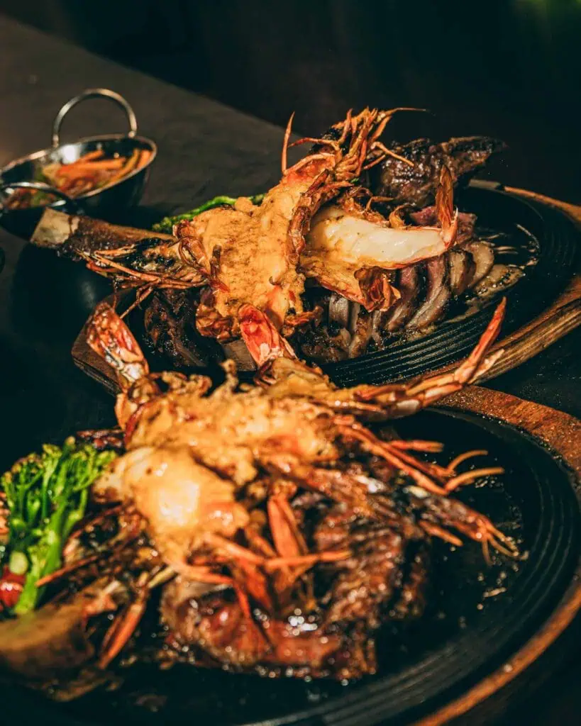 Fruits de mer et steak grillés sur une plaque en fonte chauffée, parfaits pour une soirée tapas espagnole. Frais et savoureux, idéal pour les amateurs de cuisine méditerranéenne à Las Mañas.