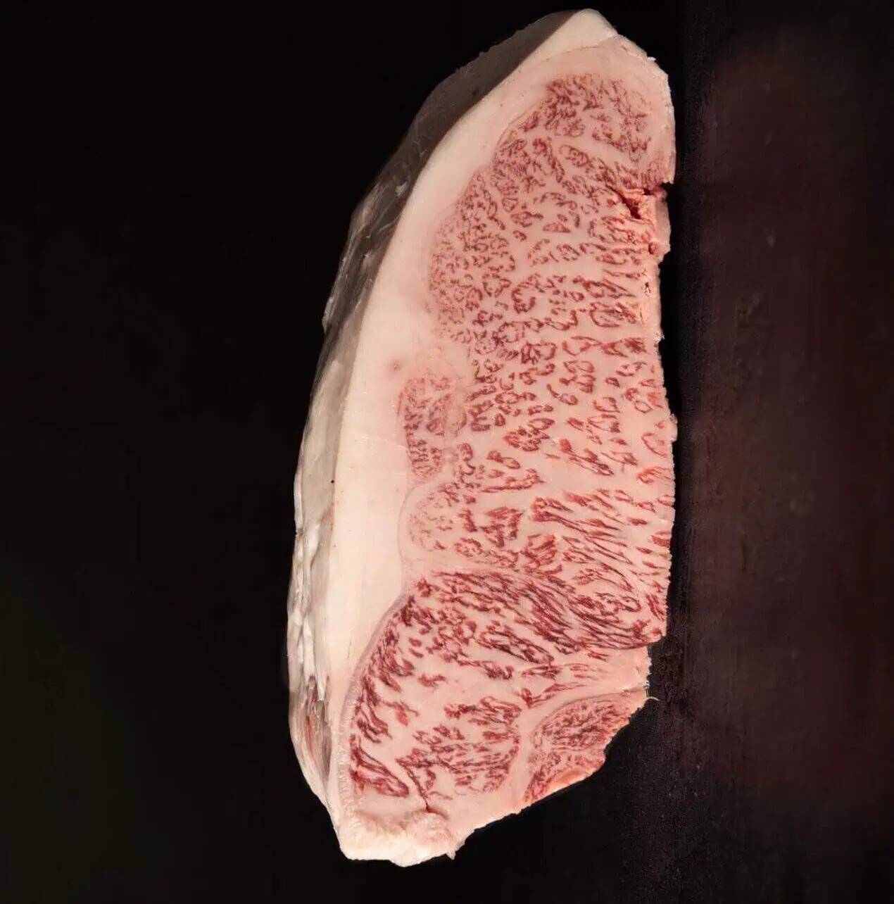 Zeldzaam Wagyu-rundvlees met schitterende marmering op een zwarte achtergrond. Perfect voor liefhebbers van topkwaliteit vlees en gastronomische delicatessen.
