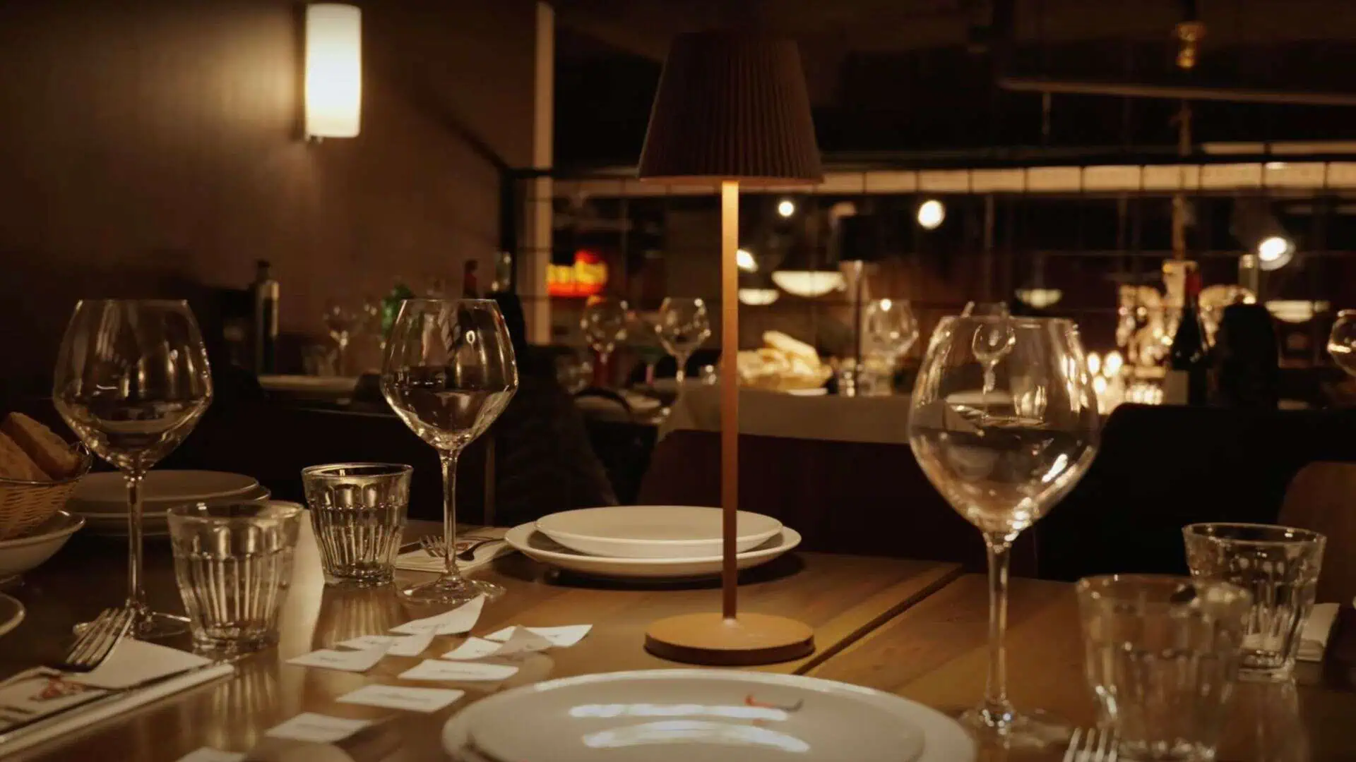 Elegant gedekte tafel in een restaurant met wijn- en waterglazen, bordjes, bestek en een sfeervol dimlicht voor een verfijnde eetervaring.