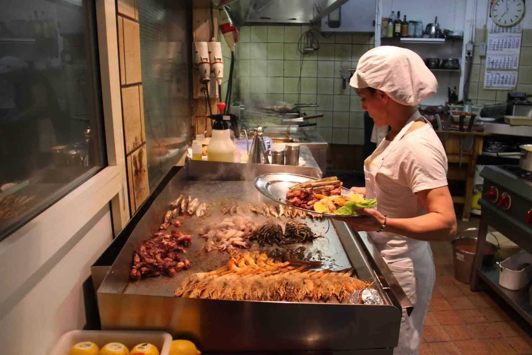 Une serveuse attentionnée prépare une assiette de tapas et de fruits de mer grillés dans un bar à tapas traditionnel espagnol ; dégustez des plats frais et savoureux chez Las Mañas.