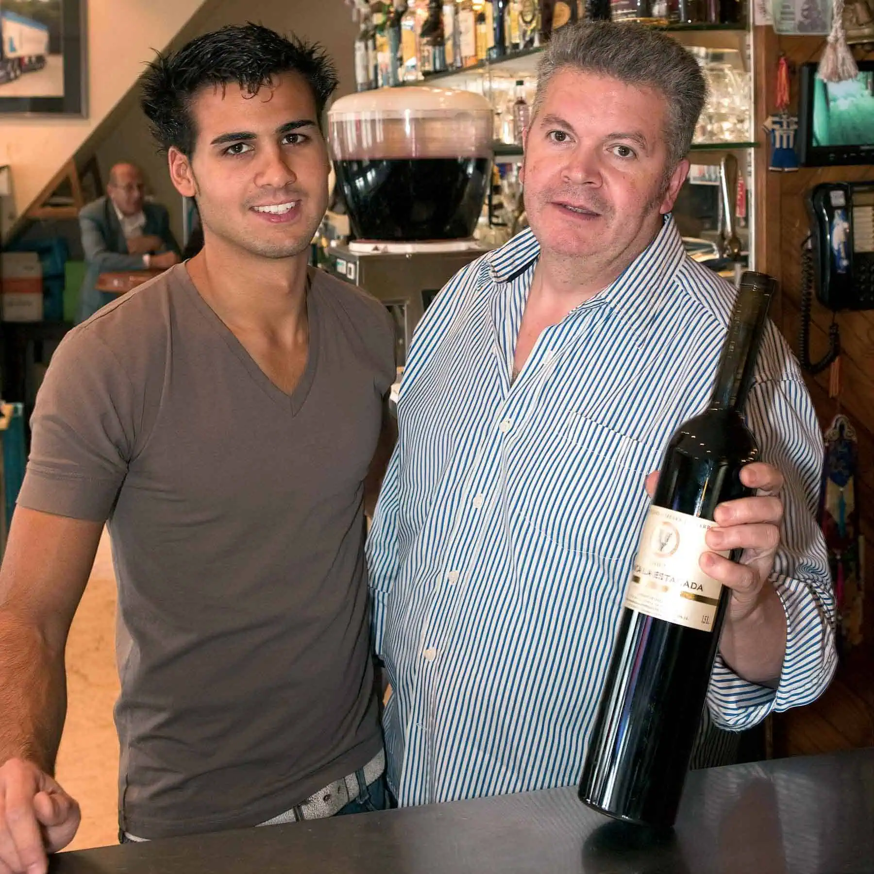 Gezellig interieur van La Mañas tapasbar met barman en gast die genieten van goede wijn, perfecte setting voor tapas en Spaanse cultuur in Brussel.