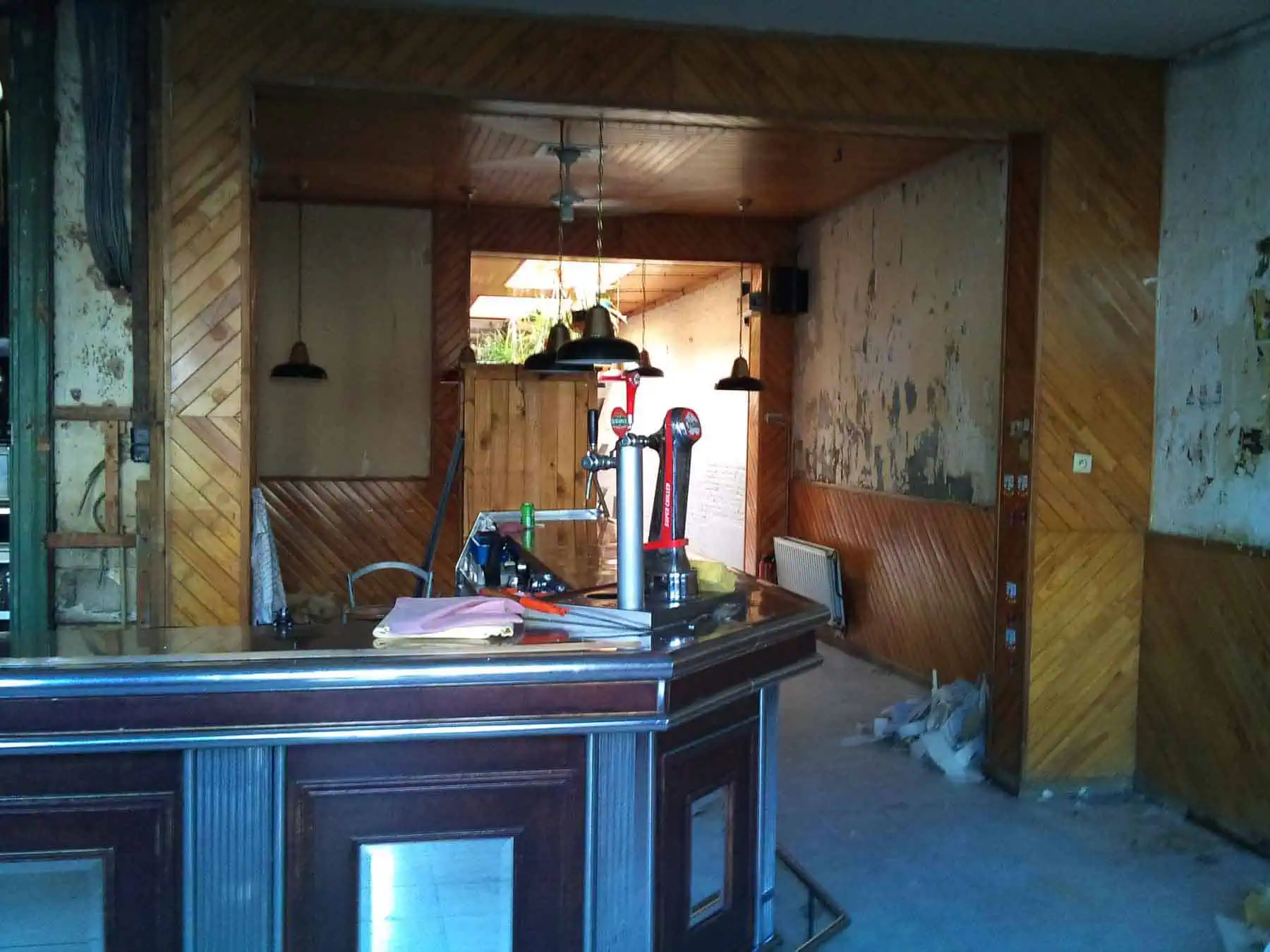 Cosy bar interior with wooden details and industrial lighting, still under finishing touches, for a revamped hospitality or dining venue.