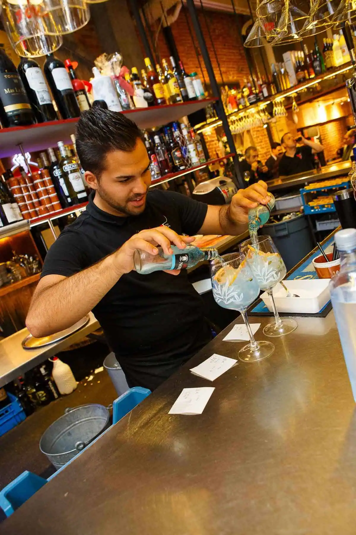 Cosy bartender makes refreshing cocktails in a cosy restaurant with open kitchen and warm atmosphere.
